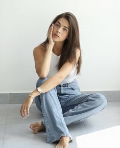 a woman sitting on the floor with her hand to her face