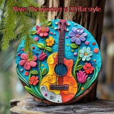 a colorful guitar shaped rock sitting on top of a tree stump with flowers and leaves painted on it