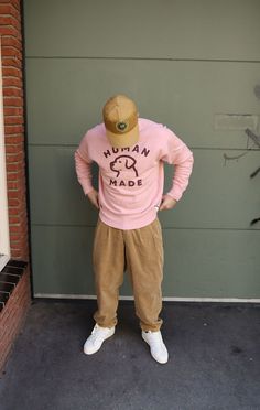 a man in a pink shirt and hat standing next to a garage door