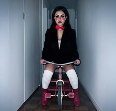 a woman sitting on top of a bike in a hallway with her legs spread out