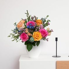 a white vase filled with lots of colorful flowers