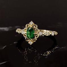 an emerald and diamond ring on a black surface