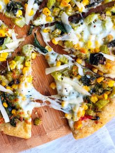 a pizza topped with cheese and vegetables on a cutting board