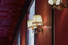 two lamps hanging on the side of a red wall