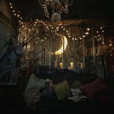 a living room filled with lots of furniture under a chandelier covered in lights