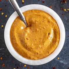 a white bowl filled with peanut butter on top of a black table next to a spoon