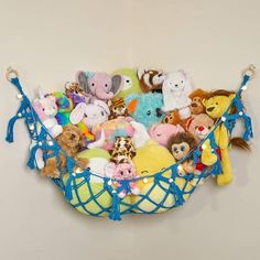 a basket filled with stuffed animals hanging on the wall next to a white wall behind it