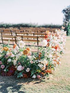 rows of wooden chairs with flowers on them in front of an empty bench at a wedding ceremony