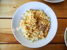 a bowl of macaroni and cheese on top of a white plate next to a bowl of broccoli