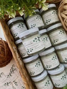 several jars of candles sitting on top of a table next to flowers and wicker baskets