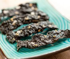 some black food is sitting on a blue and green plate with white sprinkles