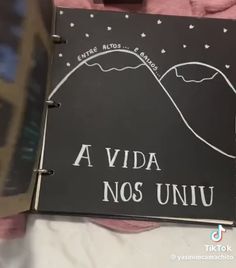 a black notebook with white writing on the front and back cover that reads, a vida nos univu