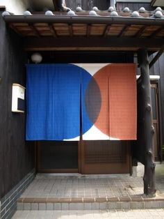 two blue and orange towels hanging on the side of a building in front of a doorway