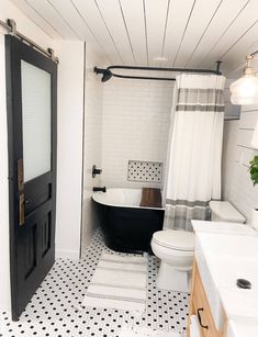 a black and white bathroom with a bathtub, toilet and sink