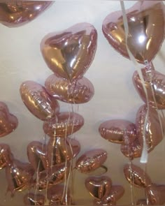 many balloons in the shape of hearts are hanging from a ceiling with white string and pink foil