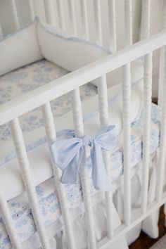 a white crib with blue and white bedding