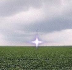 a lone white star is in the middle of a green field under a cloudy sky