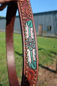 a person holding up a brown belt with flowers on it in front of a building