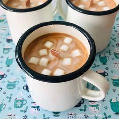 two mugs filled with hot chocolate and marshmallows on top of a table