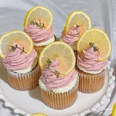 cupcakes with pink frosting and lemon slices on a white cake platter