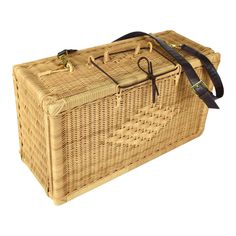 a wicker picnic basket with black straps on the handle and strap around the bottom