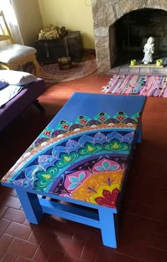 a colorfully painted table sitting in front of a fire place