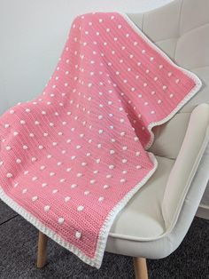 a pink and white blanket sitting on top of a chair