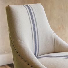 an upholstered chair with blue and white striped fabric on it's back