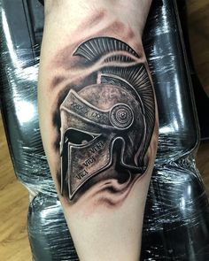 a man's leg with a spartan helmet tattoo on it