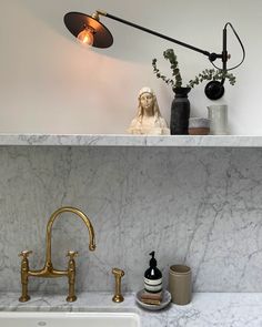 a bathroom with marble counter tops and gold faucet lights above the sink, along with soap dispensers