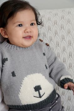 a baby wearing a sweater with a bear on it