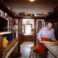 a woman standing in a kitchen next to a counter with pots and pans on it