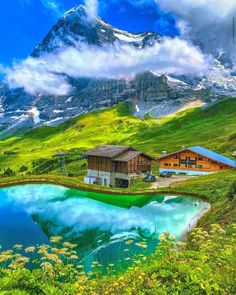 there is a house on the side of a mountain with a lake in front of it