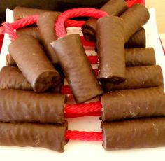 there are many pieces of chocolate wrapped in red rope on the white plate and ready to be eaten