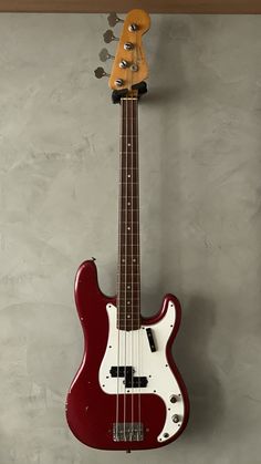 a red and white bass guitar hanging on the wall