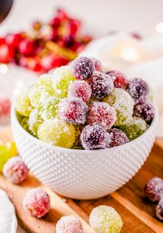 a white bowl filled with powdered sugar covered cranberries on top of a wooden cutting board