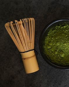 a whisk next to a green powder in a black bowl