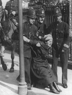 an old black and white photo of a woman being assisted by police officers on horseback