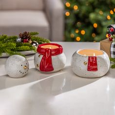 three white and red candles sitting on top of a table next to a christmas tree