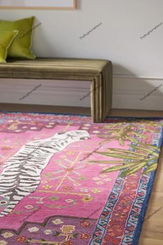 a pink area rug with an ornate design on the bottom and side, in front of a bench