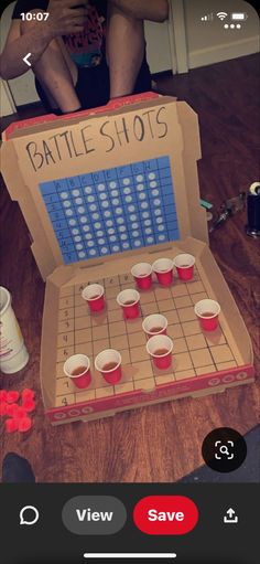 an open box with shots in it on a table next to a person sitting down