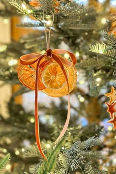 an orange slice ornament hanging from a christmas tree with star ornaments around it