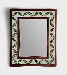 a mirror that is sitting on top of a wooden frame with flowers and leaves painted on it