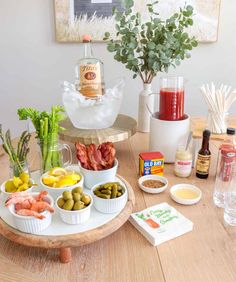 an assortment of food on a wooden table with drinks and condiments around it