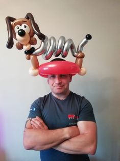 a man standing in front of a balloon dog on top of a red frisbee