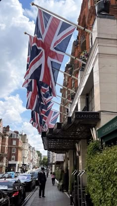 two people walking down the sidewalk with an union jack flag hanging from a clothes line