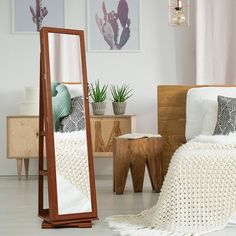 a mirror sitting on top of a wooden floor next to a white bed in a room