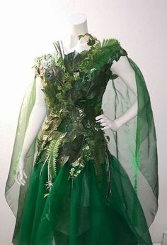 a mannequin wearing a green dress with leaves on it's chest and cape