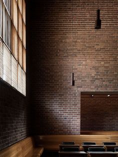 an empty room with wooden benches and brick walls