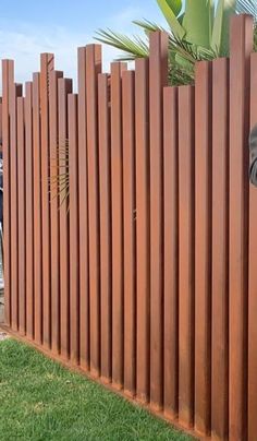 a man standing in front of a wooden fence talking on a cell phone while holding a camera